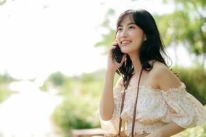 Portrait of asian young woman traveler with weaving hat, basket, mobile phone and camera on green public park background. Journey trip lifestyle, world travel explorer or Asia summer tourism concept. photo