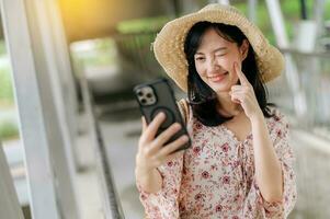 young asian woman traveler with weaving basket selfie with mobile phone and standing on overpass. Journey trip lifestyle, world travel explorer or Asia summer tourism concept. photo