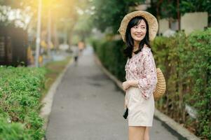 Portrait of asian young woman traveler with weaving hat and basket happy smile on green public park nature background. Journey trip lifestyle, world travel explorer or Asia summer tourism concept. photo