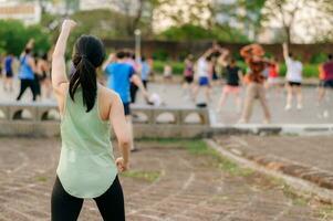 Female jogger. Fit young Asian woman with green sportswear aerobics dance exercise in park and enjoying a healthy outdoor. Fitness runner girl in public park. Wellness being concept photo