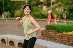 hembra persona que practica jogging. ajuste joven asiático mujer con verde ropa de deporte aeróbicos danza ejercicio en parque y disfrutando un sano exterior. aptitud corredor niña en público parque. bienestar siendo concepto foto