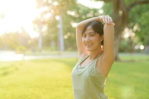 hembra persona que practica jogging. ajuste joven asiático mujer con verde ropa de deporte extensión músculo en parque antes de corriendo y disfrutando un sano exterior. aptitud corredor niña en público parque. bienestar siendo concepto foto