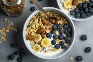 Bowl of greek yogurt with oatmeal granola, banana, blueberry, nuts, chia seeds and honey on gray table. Top view, generate ai photo