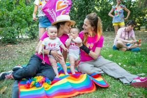 dos mujer en amor en el parque con su gemelo hijas foto