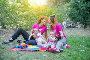 dos mujer en amor en el parque con su gemelo hijas foto