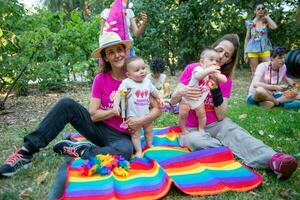 dos mujer en amor en el parque con su gemelo hijas foto