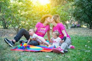 dos mujer en amor en el parque con su gemelo hijas foto