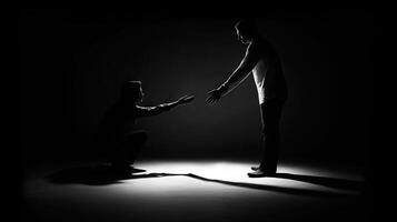 Silhouette of a man with another one in dark room. Giving hand of help. . photo