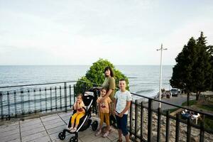 Portrait of a happy family standing at the seaside with baby carriage in Nessebar. photo