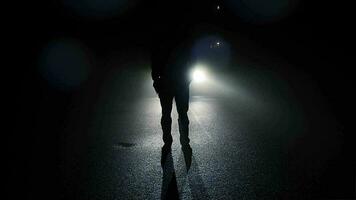 Person walking outside on dark spooky street at night video