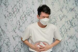 Man puts on a face mask tummyache isolated on White background,pandemic and social distancing concept.Covid-19 photo