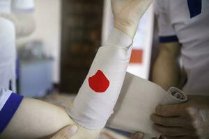 primero ayuda formación a envolver el herida alrededor brazo con vendaje en brazo a detener el sangrado foto