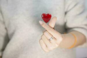 mini heart of gril showing love finger shape and 3d red heart closeup photo