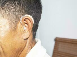 An old man wears a hearing aid, closeup photo