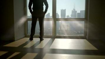 Young Businessman Overlooking Urban City Skyline Standing at Window looking outside video