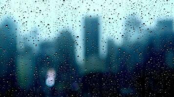 Rain drops pouring down on window glass with urban city skyline view on a rainy weather day video
