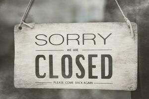 A closed sign posted on glass door of store. Concept of shop service business closed on holidays. photo