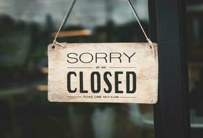 A closed sign posted on glass door of store. Concept of shop service business closed on holidays. photo