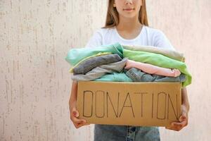 Girl holding donation box with with summer clothes. photo