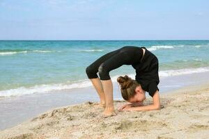 Girl doing sports exercises on the beach. photo