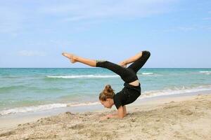 Girl doing sports exercises on the beach. photo