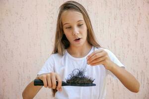 el niña es sorprendido, porque allí es un lote de pelo en el peine. foto