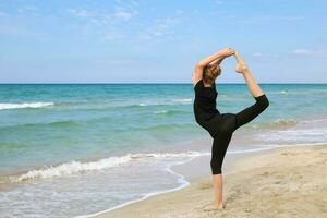 niña practicando yoga en playa. foto