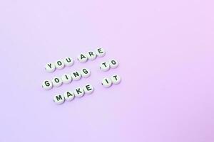 Top view of You are going to make it quotes made out of beads on pastel background. motivation and success concept photo