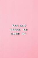 Top view of You are going to make it quotes made out of beads on pastel background. motivation and success concept photo