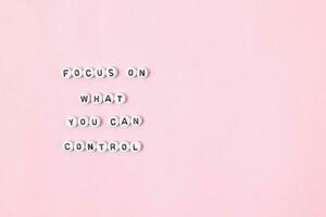 Top view of focus on what you can control quotes made out of beads on pink background. motivation and success concept photo