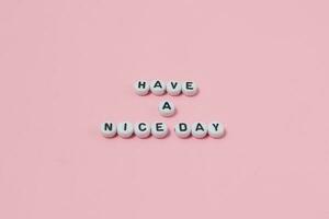 Top view of Have a nice day quotes made out of beads on pink background. motivation and success concept photo