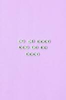 Top view of it is okay not to be okay quotes made out of beads on pastel background. motivation and success concept photo