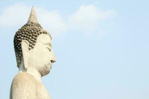Beside ancient head and shoulder of Buddha statue and light blue sky. photo