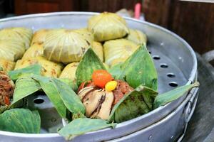 The rice wrapped in Lotus leaf are in steamer and open one for present ingredient in lotus leaf wrap , Chinese food inThailand. photo