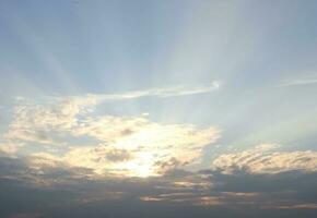 Cloud and sunlight through the cloud with light blue sky, gray cloud at the bottom of pictiure and sun behind the clouds. photo