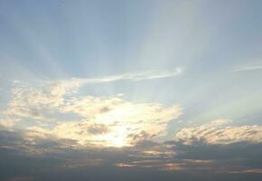 Cloud and sunlight through the cloud with light blue sky, gray cloud at the bottom of pictiure and sun behind the clouds. photo