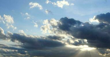 Gray clouds group and sun behind with sunlight through the cloud and blue sky. photo