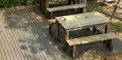 Set of retro style wood table and bench on wood floor outside of building. photo