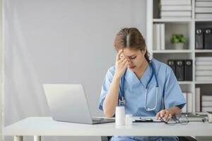 estresado joven hembra médico mirando a ordenador portátil leyendo malo Noticias en línea preocupado de Error a lugar de trabajo. infeliz profesional médico en tensión sensación cansado resolviendo computadora problema a trabajar. foto