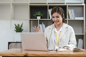 Asian call center with headset and microphone working on her laptop. Female operator provide exceptional customer service. Supportive call center agent helping customer on inquiry. Enthusiastic photo