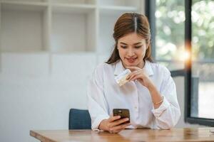 hermosa joven asiática sosteniendo un teléfono inteligente y usando tarjeta de crédito para comprar en línea. foto