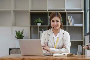 Asian call center with headset and microphone working on her laptop. Female operator provide exceptional customer service. Supportive call center agent helping customer on inquiry. Enthusiastic photo