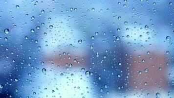 Rain drops pouring down on window glass with urban city skyline view on a rainy weather day video