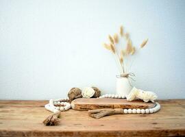 Stylish composition of table with beads and flowers and crown, bench in retro style, clay vases and crockery. Rustic inspiration. Summer vibes. Beige wood table. photo