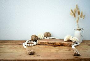 Stylish composition of table with beads and flowers and crown, bench in retro style, clay vases and crockery. Rustic inspiration. Summer vibes. Beige wood table. photo