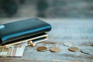 Leather wallet, with Russian money on a wooden table - 100 Russian rubles and coins. Cash notes. Poverty, inflation. photo