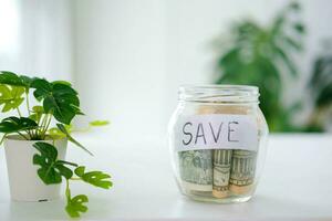 Glass jar with dollars and text save. Money saving concept. Credit. Copy space. photo