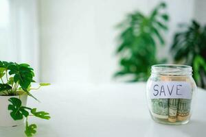 Glass jar with dollars and text save. Money saving concept. photo