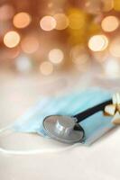 Medical stethoscope and madical mask on gold blurred background. photo