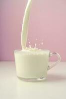 Milk is poured into a transparent cup on a purple background. photo